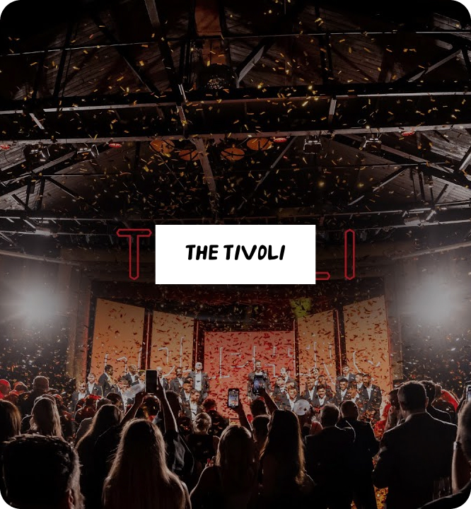 A crowd watches a stage performance at The Tivoli venue, with bright lights and confetti falling from above. The words "THE TIVOLI" are displayed prominently at the center.