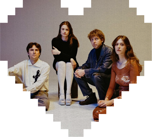 Four people sit together inside a white, pixelated heart frame. Two women and two men face forward; one woman wears black, the other wears brown stripes, while the men wear light and denim outfits.