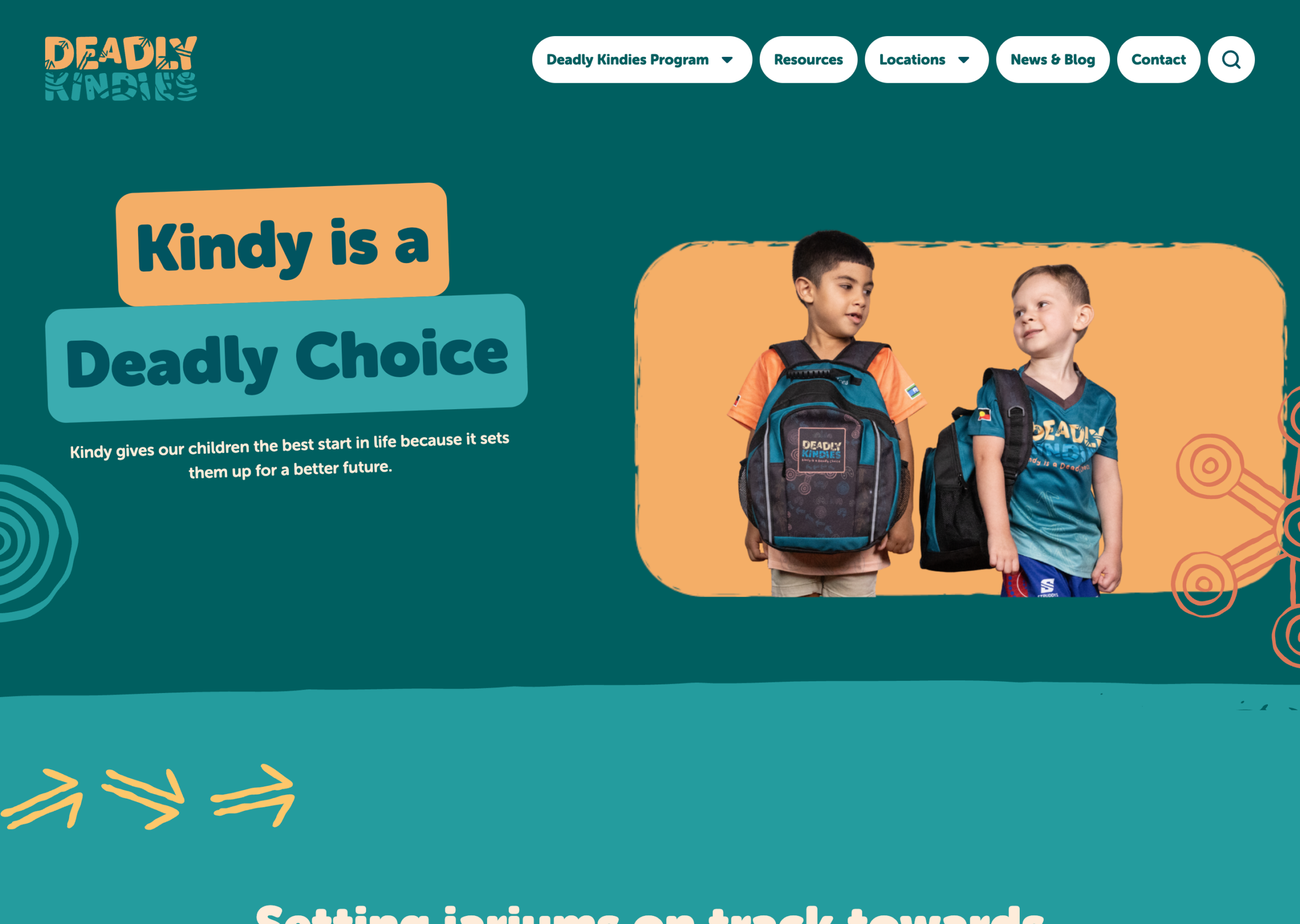 Two young boys with backpacks stand side by side, smiling. Text reads "Kindy is a Deadly Choice," promoting early education. The background is teal with decorative orange elements and the Deadly Kindies logo at the top left.
