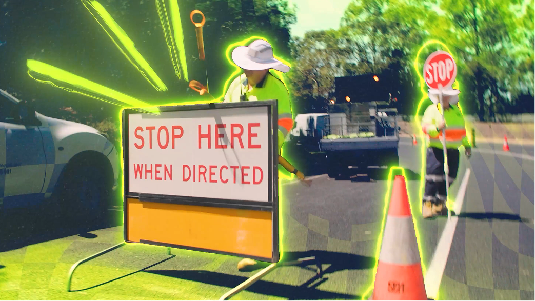 A worker in a hat and safety vest holds a “STOP” sign on a road next to a sign reading “STOP HERE WHEN DIRECTED,” with orange traffic cones and a white vehicle nearby. Bright green lines highlight the scene.